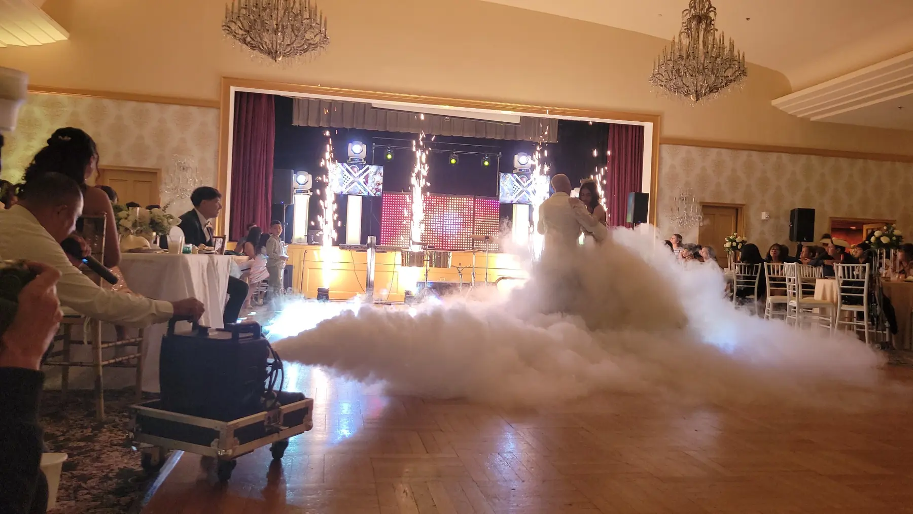 Pareja de boda bailando entre nubes y fuentes de pirotecnia fría
