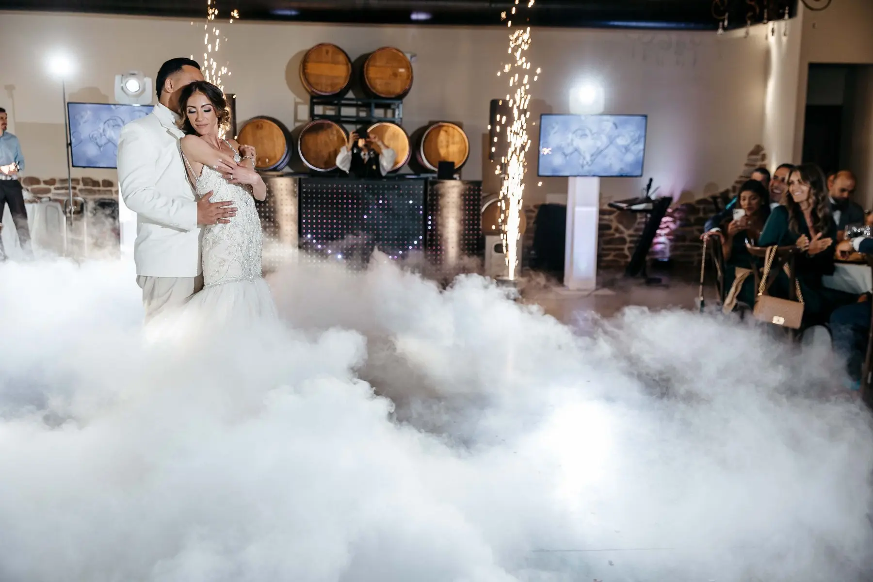 Novios abrazados entre nubes y pirotecnia fría