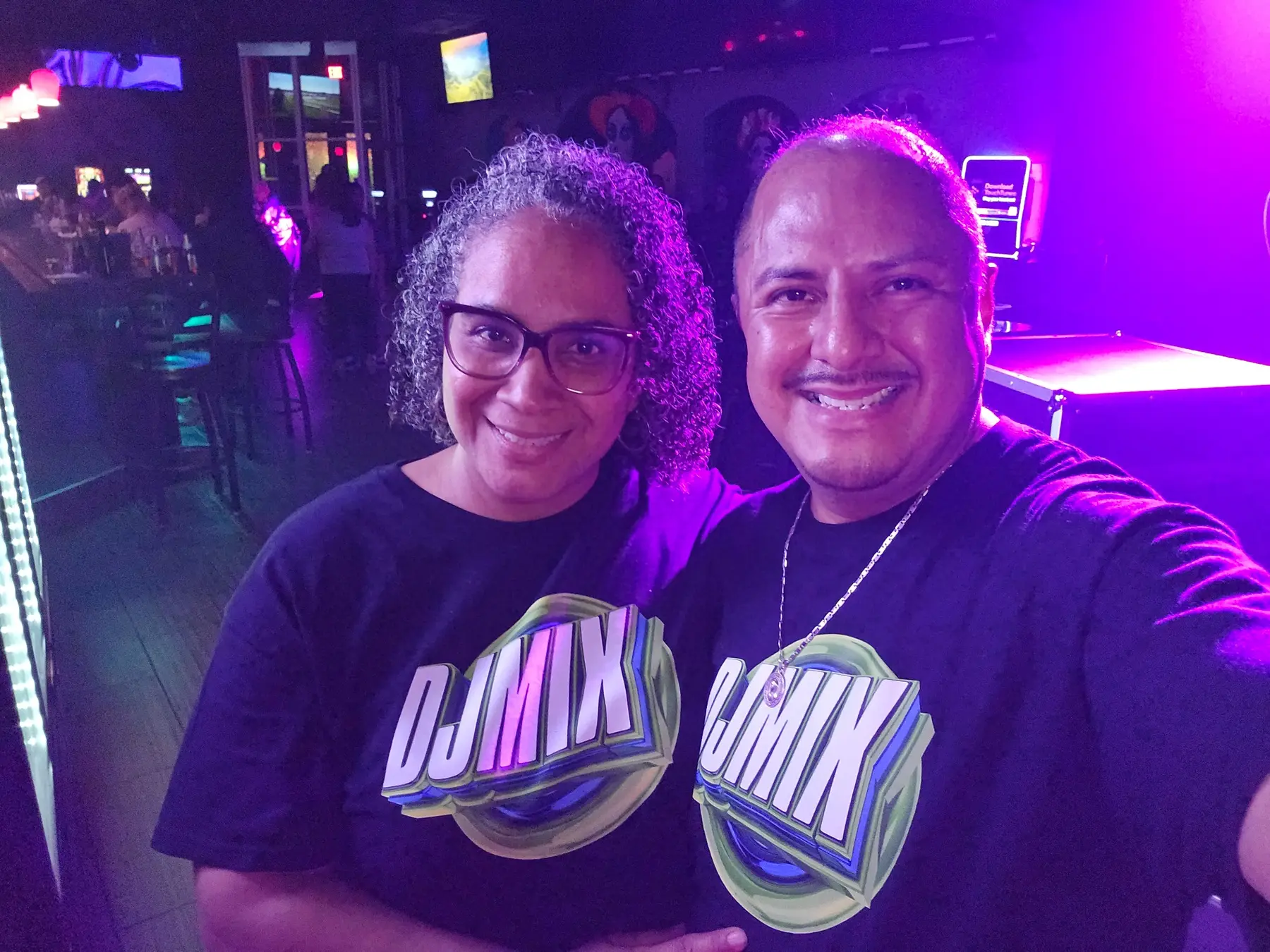 Equipo DJMIX uniformado durante un evento con iluminación magenta