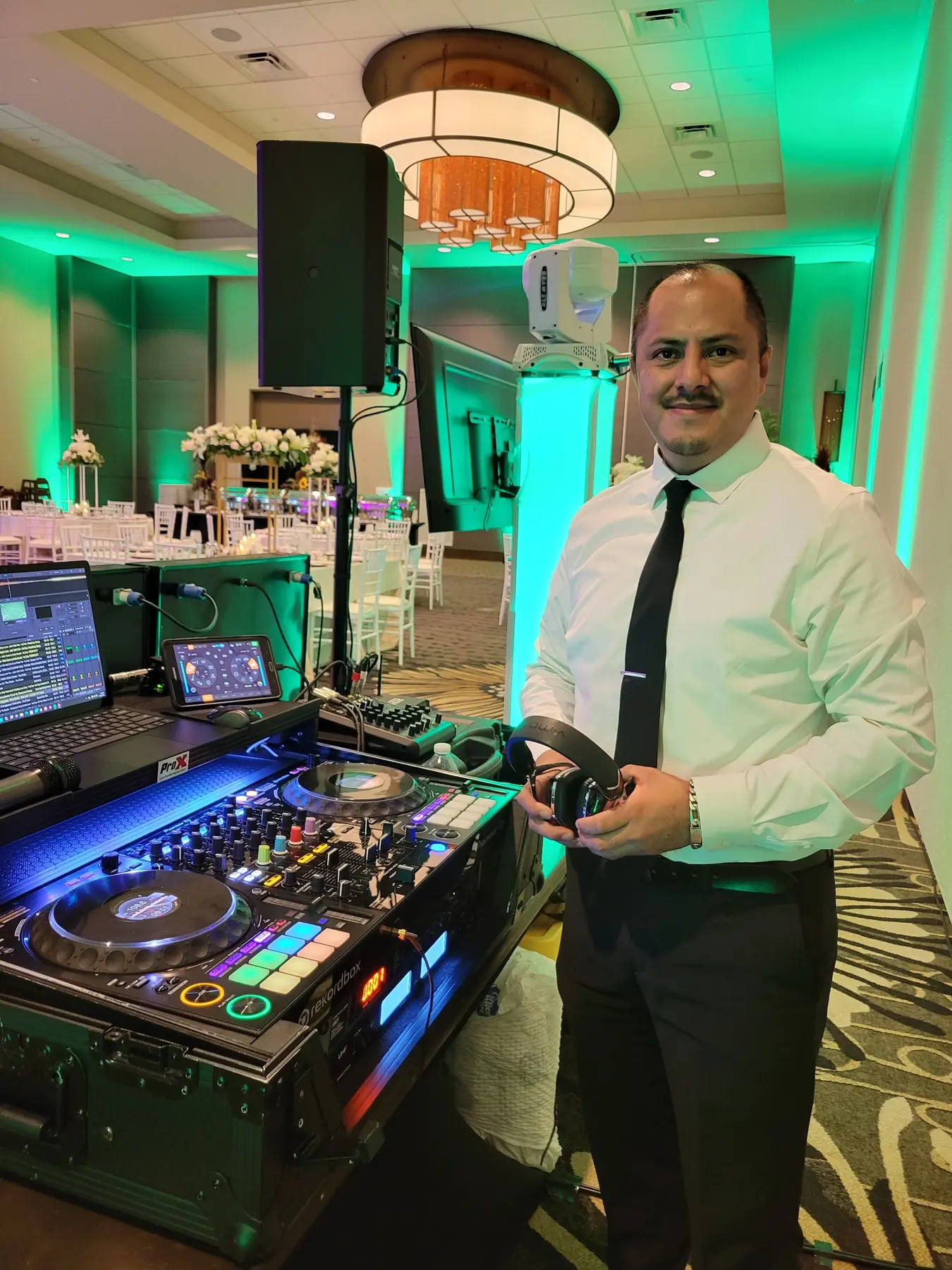 DJMIX junto a su cabina profesional en un salón iluminado